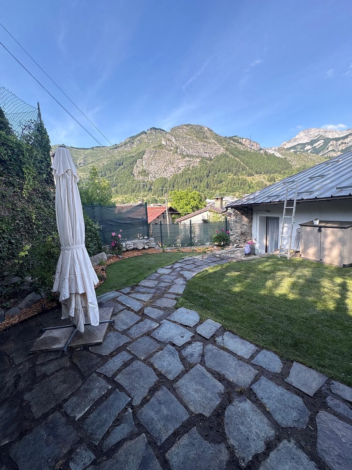Giardino di montagna curato da Lisa Garden: prato nuovo, vialetto in pietra e montagne sullo sfondo