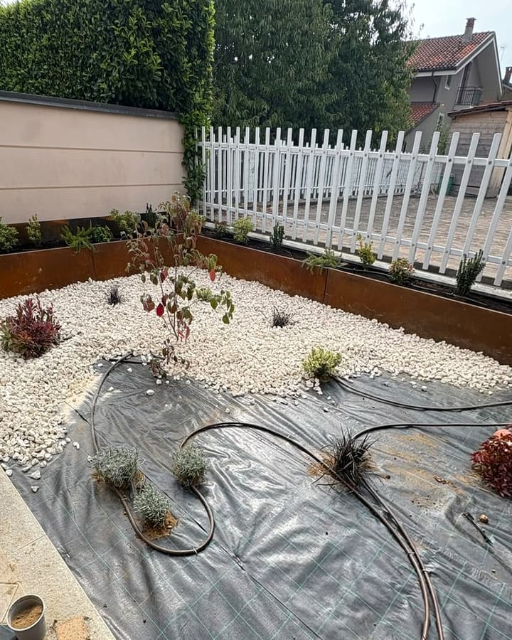 Linea di irrigazione a goccia posata sul telo antierba in un'aiuola con ghiaia chiara